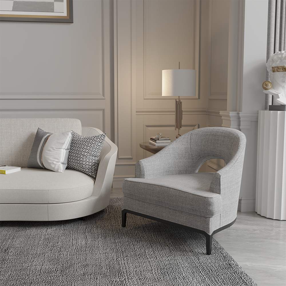 Neutral living room with a beige sofa, gray armchair, and patterned throw pillows beside a side table with a lit lamp.