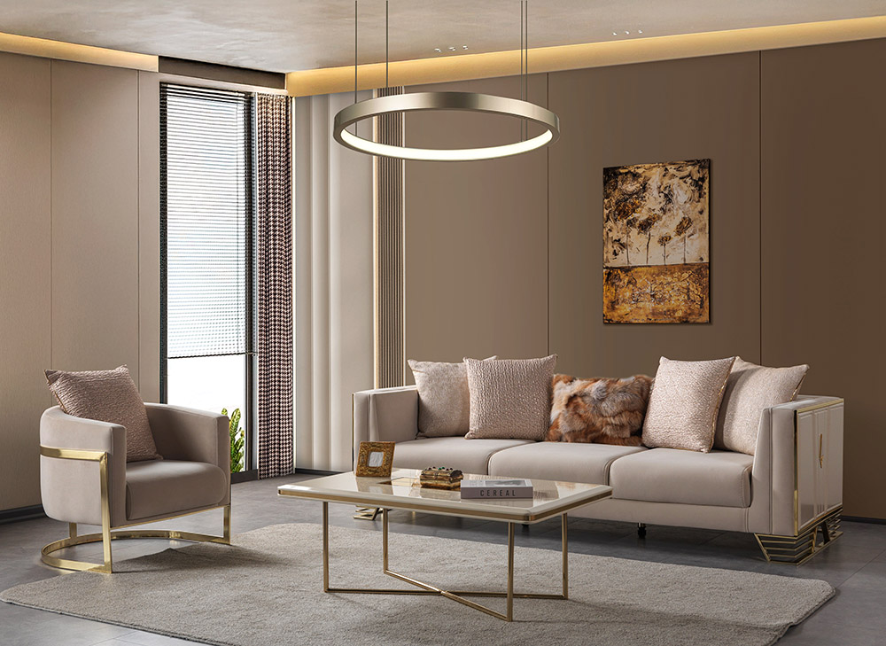 Anka Living Room 12 Armonna Modern beige living room with a sofa and armchair gold accents circular pendant light glass coffee table abstract wall art and a large window with blinds