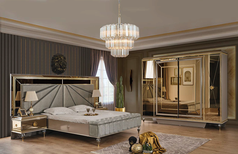 Luxurious master bedroom with a tufted gray bed, gold-trimmed mirrors, and a crystal chandelier.