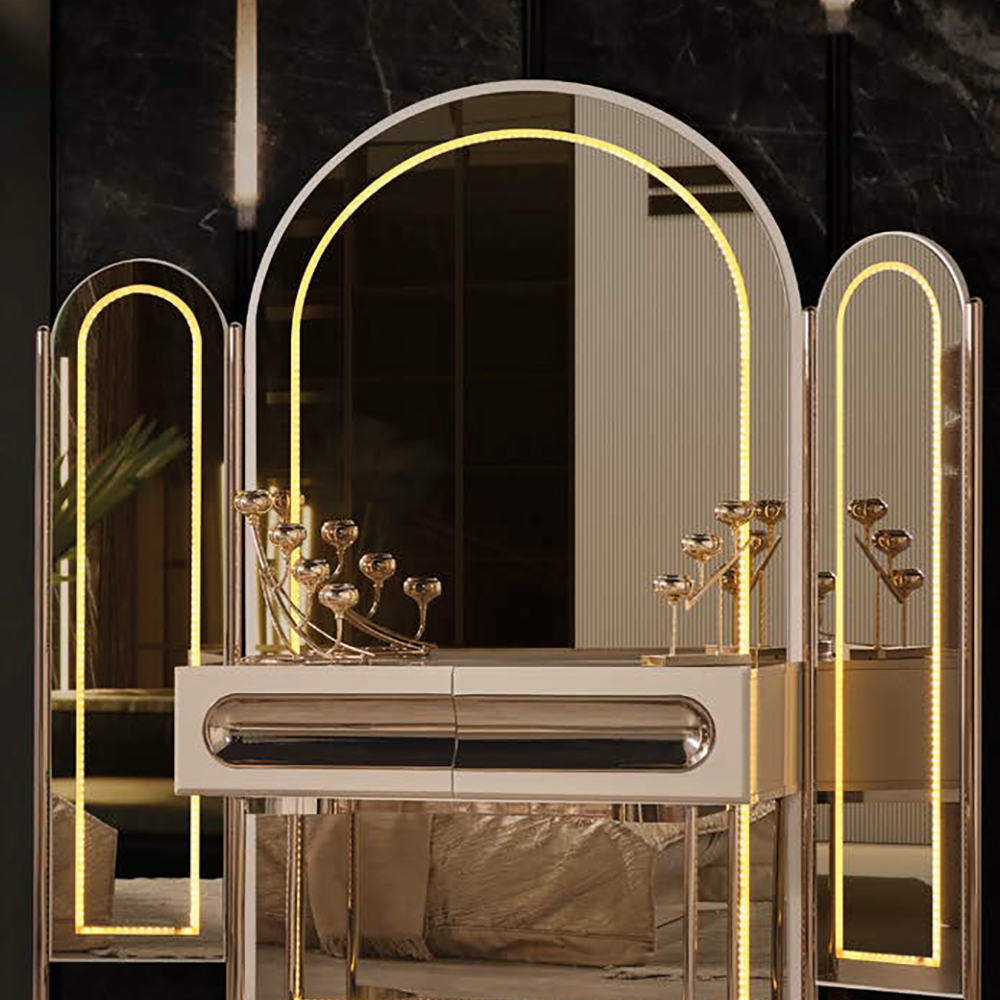 Luxurious gold vanity with arched mirrors, warm LED lighting, a white drawer and decorative candle holders in a dim room.