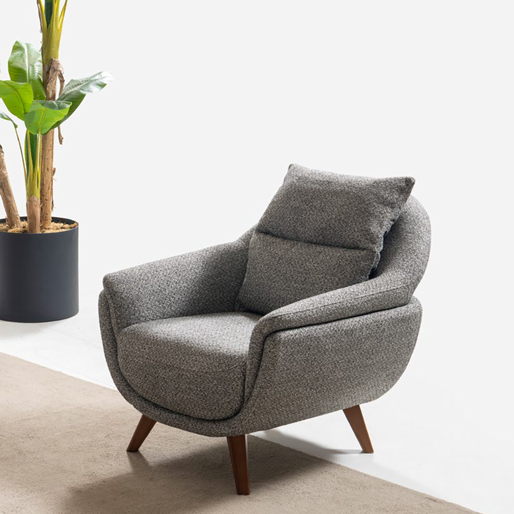 Gray textured armchair with wooden legs sits on a beige rug beside a tall potted green plant.