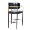 Black leather bar stool with a gold metal frame and footrest standing on slender black legs