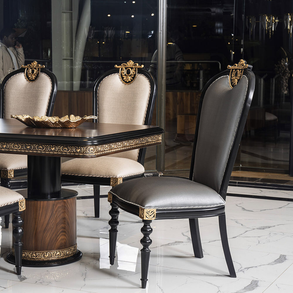 Luxurious dining room with black and gold upholstered chairs around a carved table with marble floor.