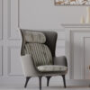 Gray high back armchair with striped cushions in a light paneled living room featuring a mantelpiece and neutral decor