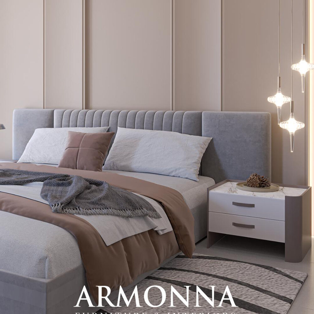 Modern bedroom setup featuring a grey tufted headboard bed with beige and light gray bedding, cream walls, a white marble-topped nightstand, and hanging pendant lights on the right.