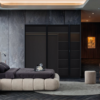 Modern bedroom with a low beige platform bed dark bedding wooden nightstands and a lake view through large windows