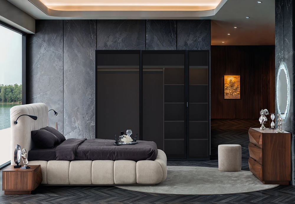 Modern bedroom with a low beige platform bed, dark bedding, wooden nightstands, and a lake view through large windows.