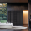 Modern bedroom with dark wood walls large windows a white bed and a black wardrobe set against a circular rug