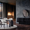 Dio Dining Room Armonna Modern dining room with a rectangular table and four white upholstered chairs around a circular rug beside a lit fireplace