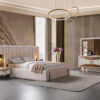 Luxurious bedroom with a plush upholstered bed gold accents and a white dresser with a large mirror
