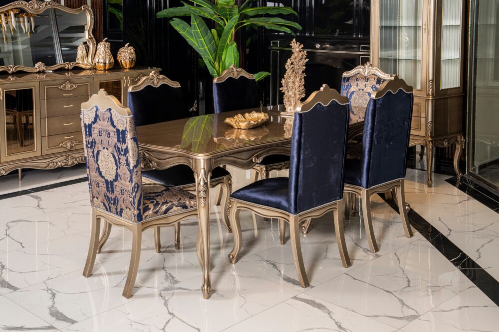 Emirgan Classic Set 2 Armonna Luxurious dining room with gold trimmed chairs around a glass top table and blue velvet upholstery