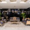 Luxurious living room with blue and gold upholstered sofas and chairs marble floor and a gold accented coffee table under a blue chandelier