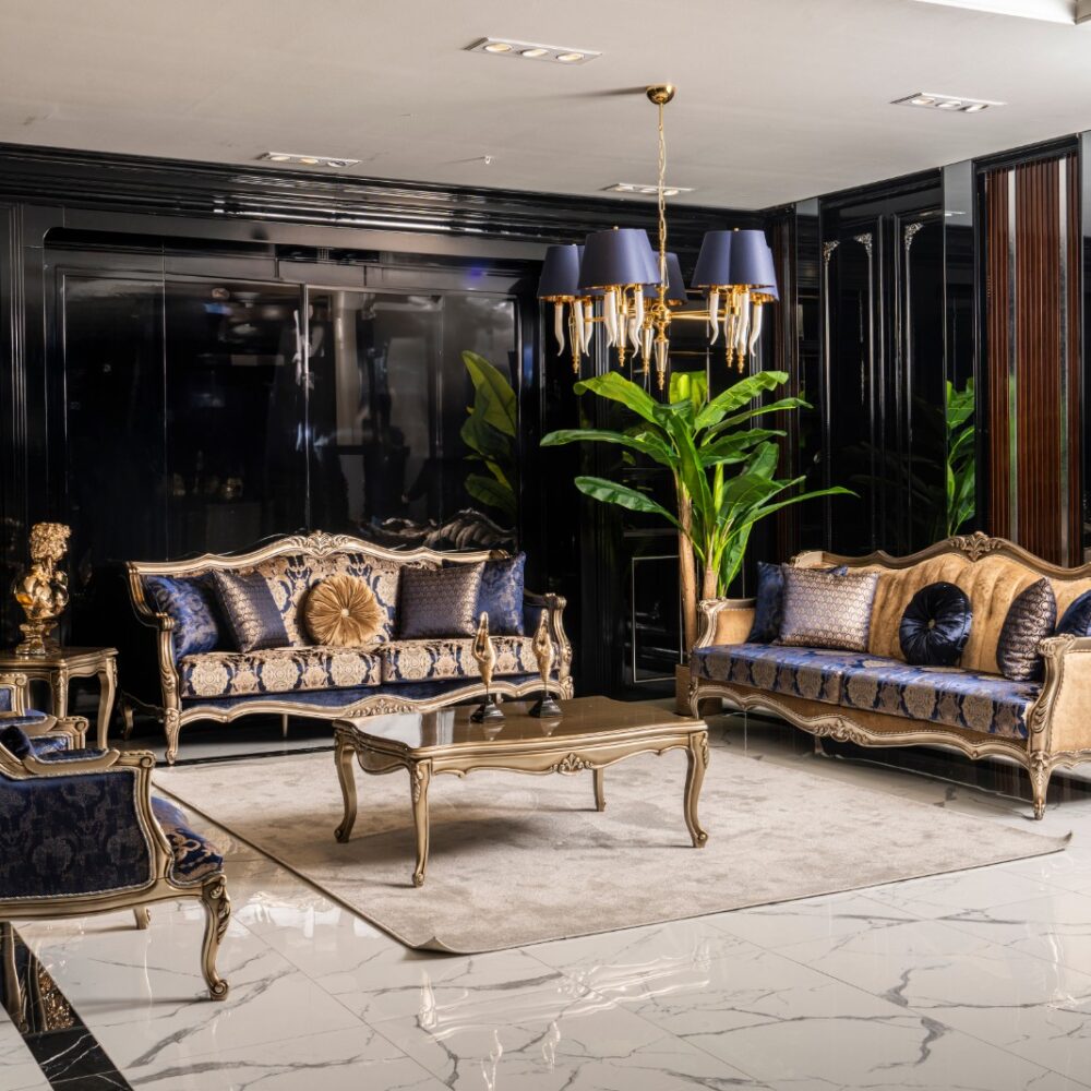 Luxurious living room with ornate gold and blue upholstered sofas, matching chairs, a glass coffee table, and a chandelier.