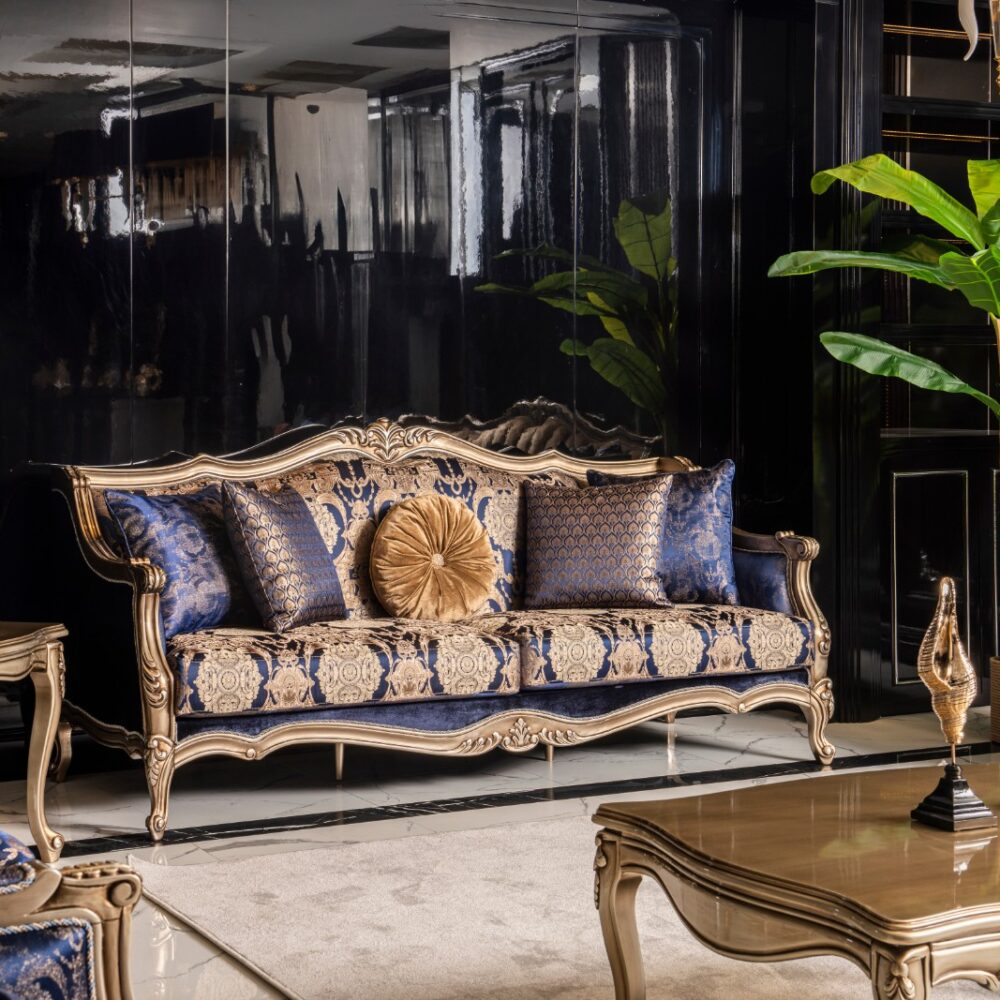 Luxurious living room with gold-framed blue patterned sofa and matching cushions, black mirrored walls, and a tall green plant nearby.