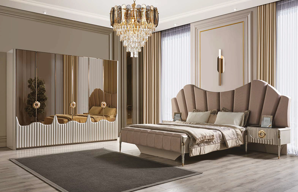 Luxurious bedroom with scalloped beige upholstered headboard, crystal chandelier, and mirrored wardrobe.