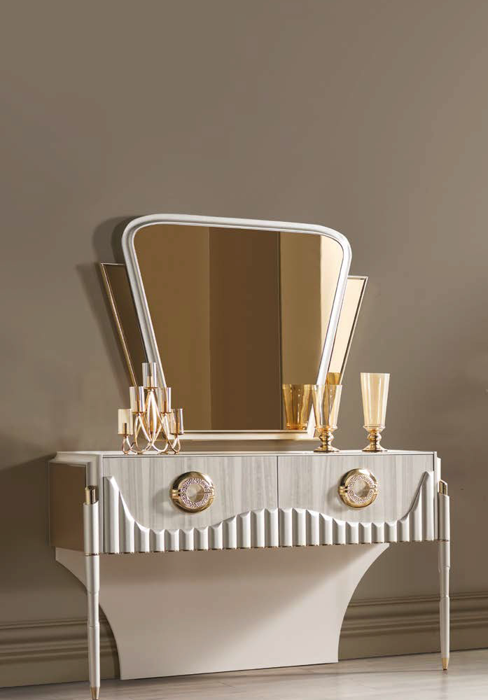 Silver, art-deco style dresser with a curved, matching mirror; topped with gold candle holders and two tall gold goblets.