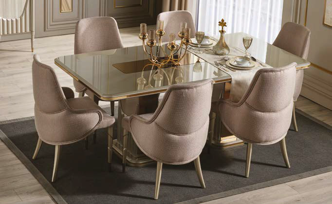 Elegant beige upholstered dining chairs surround a glass dining table with a gold-toned candelabrum centerpiece.