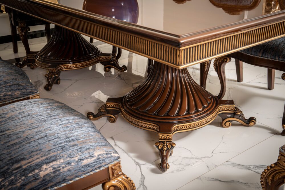 Gize Classic Set 10 Armonna Close up of an ornately carved dining table pedestal with fluted dark wood base and gold trim on a marble floor