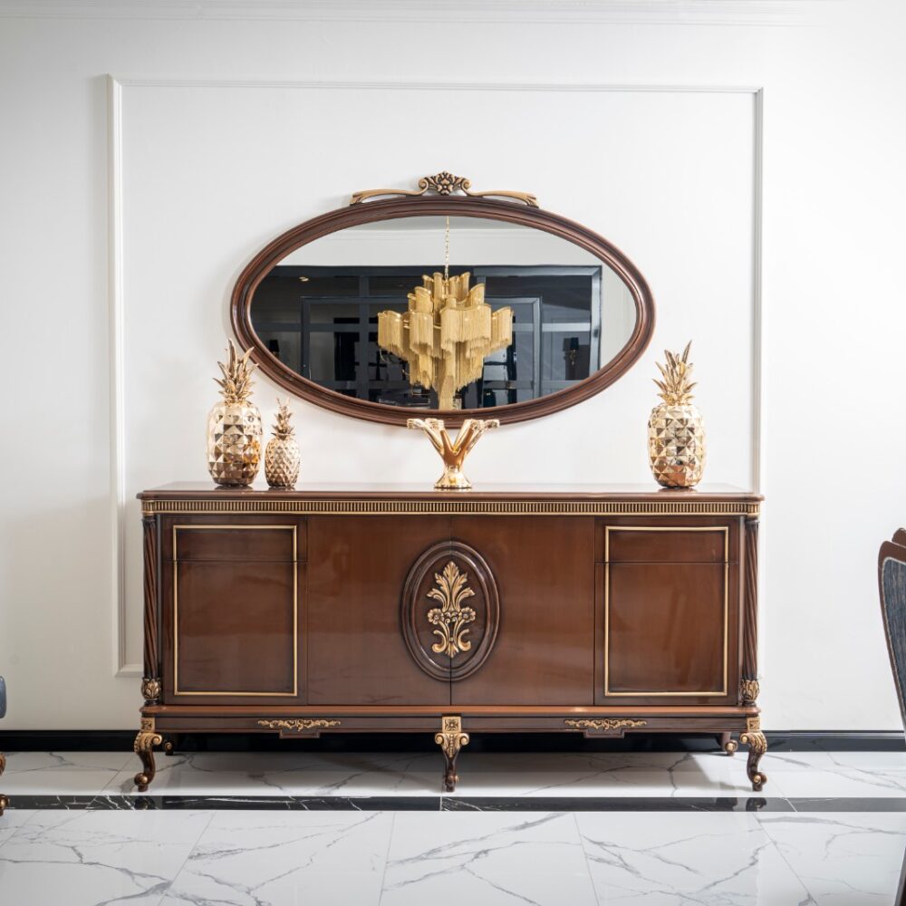 Antique mahogany sideboard with gilded accents and an oval mirror, flanked by gold pineapple decorations.