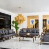 Luxurious living room with blue velvet sofas gold accented legs and a large gold chandelier over a marble floor