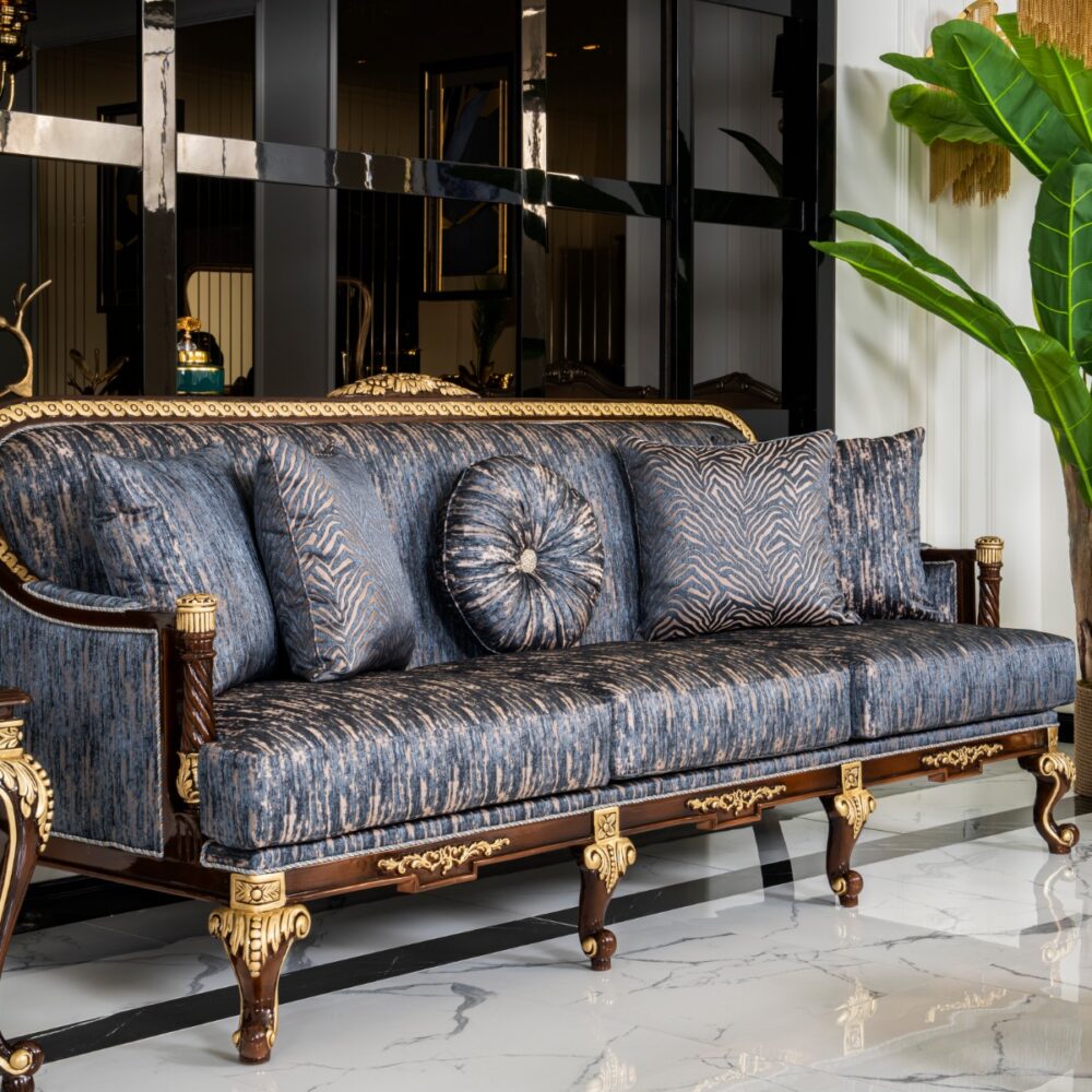 Luxurious living room scene with a blue patterned sofa and gold ornate legs, plus matching cushions and a large green plant nearby
