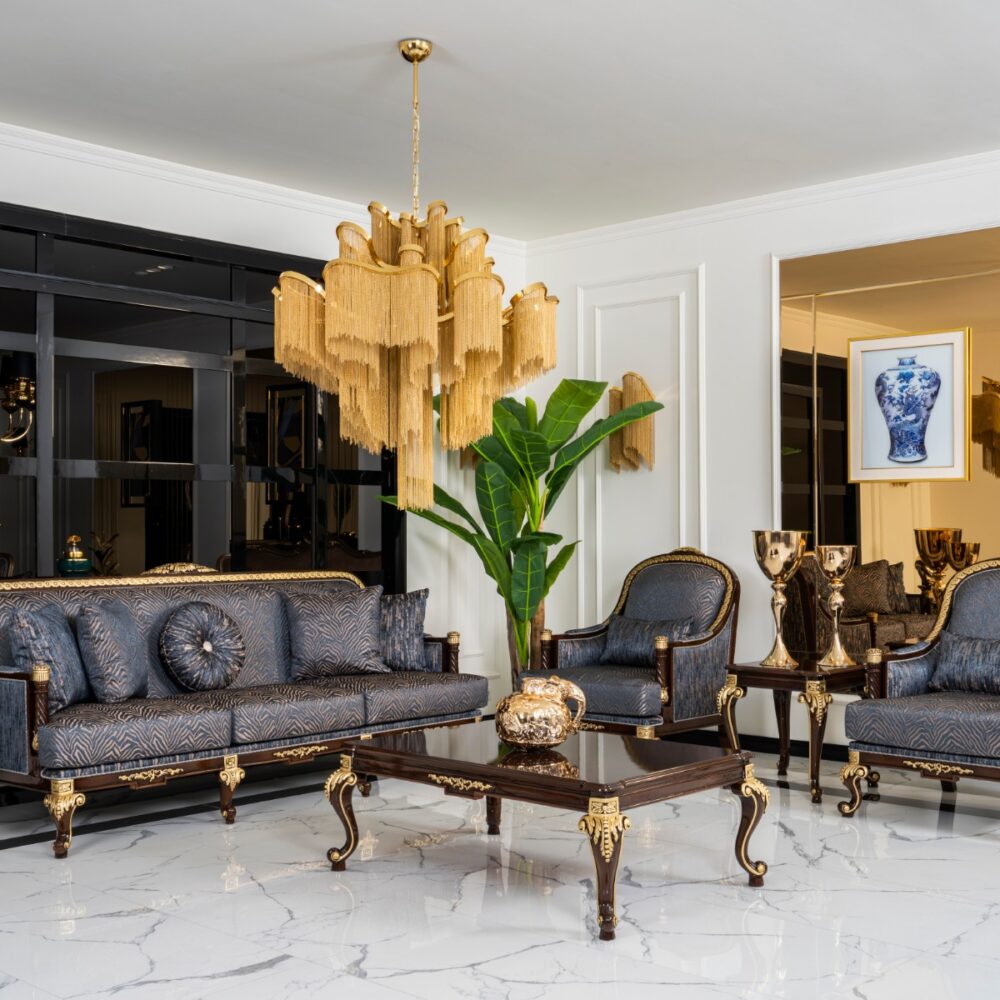 Luxurious living room with a gold chandelier, blue patterned sofas, and gilded coffee tables on a white marble floor.
