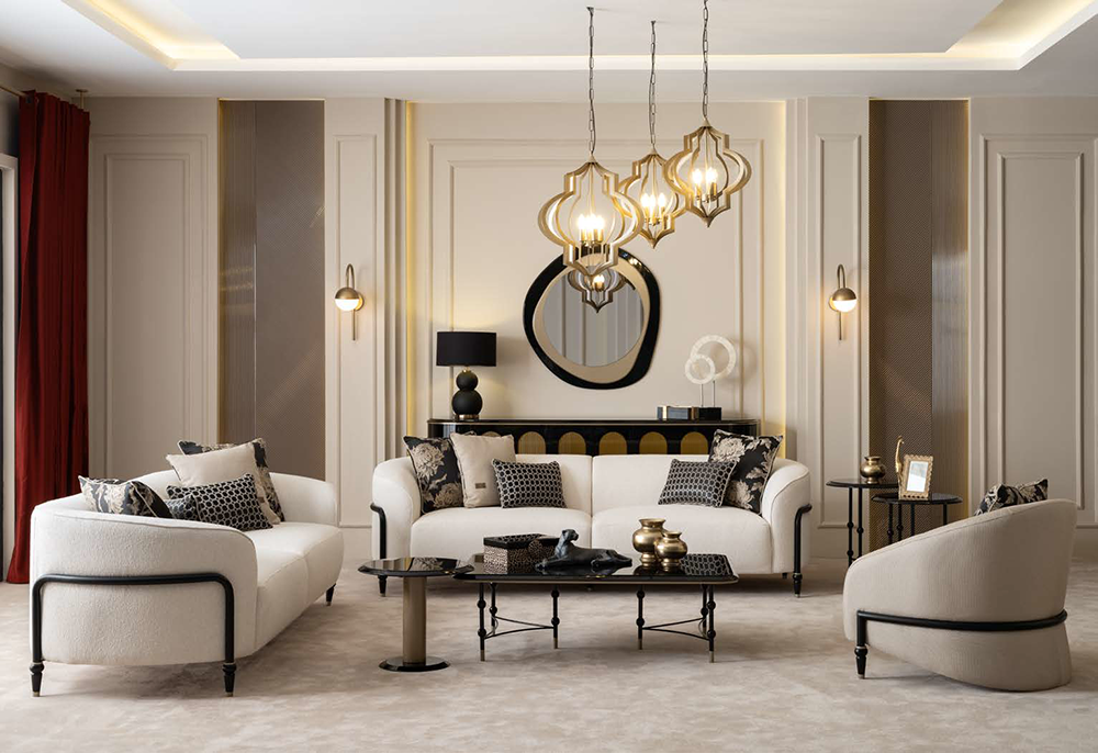 Luxurious living room with cream sofas and patterned cushions, a round mirror above a black console, and gold pendant lights over a glass coffee table.