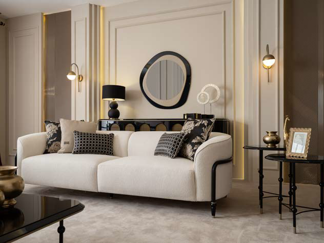 Luxurious living room with a white sofa, black accents, round wall mirror, and gold-trimmed walls