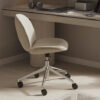 Beige cushioned swivel office chair under a wooden desk with a monitor keyboard headset and a small speaker on the desk