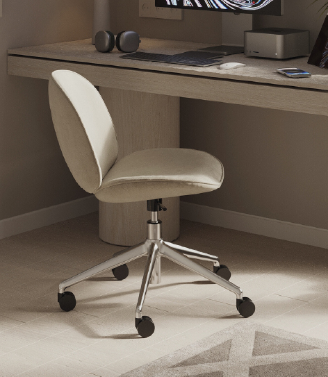 Beige cushioned swivel office chair under a wooden desk with a monitor, keyboard, headset, and a small speaker on the desk.