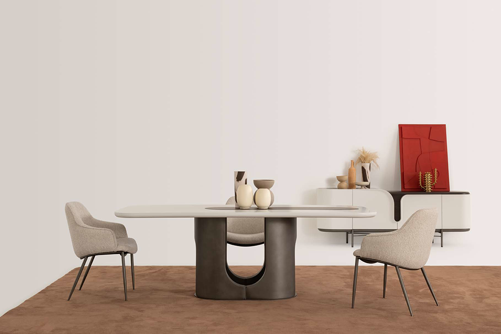 Modern dining room with a round white table on a dark curved pedestal base, surrounded by four beige upholstered chairs.