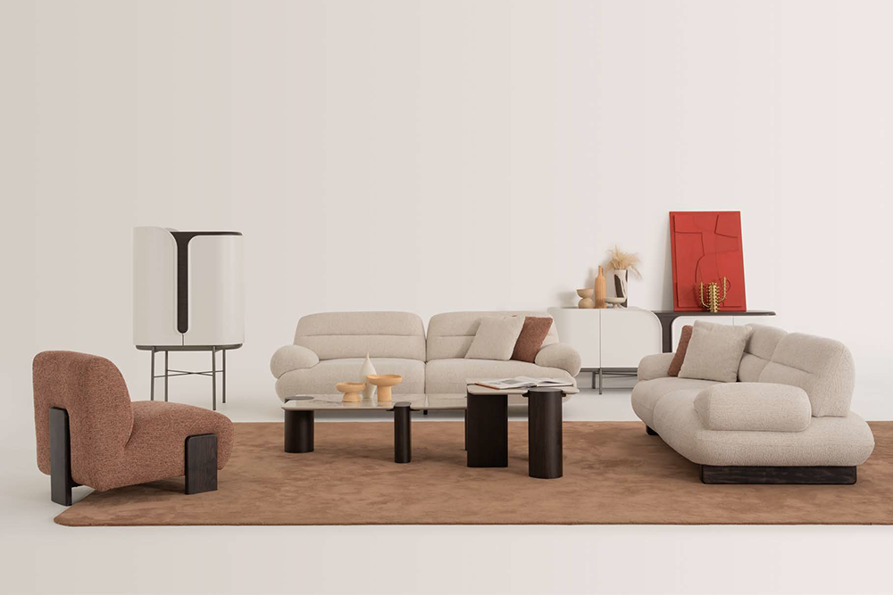Contemporary living room furniture setup with a beige sectional sofa, a rust-colored lounge chair, and black cylindrical coffee tables on a brown rug in a minimalist setting.