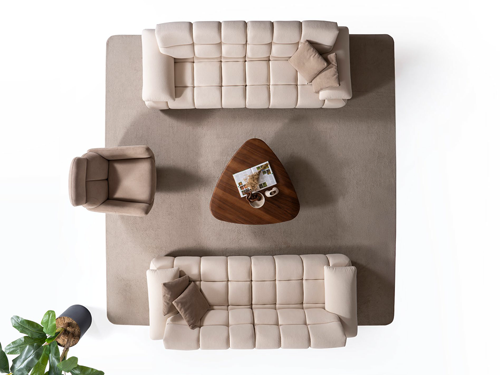 Liberta Living Room 3 Armonna Overhead view of a beige sectional sofa arrangement around a triangular wooden coffee table on a large beige rug with a magazine on the table