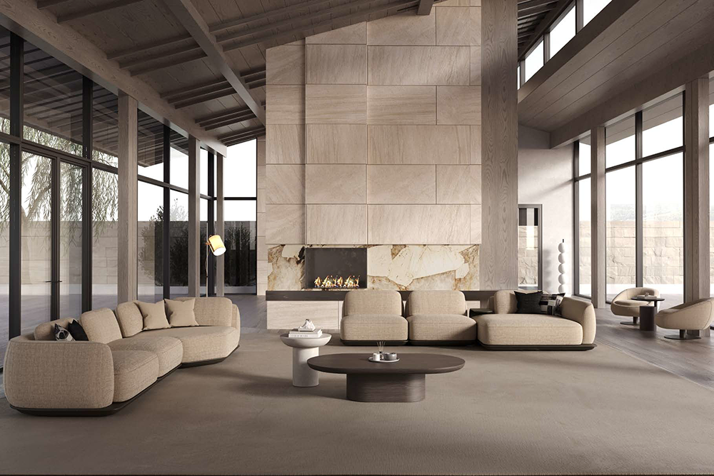 Spacious modern living room with a tall stone fireplace, beige curved sofas, and floor-to-ceiling glass walls.