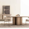 Modern dining room with a round table on a brass cylindrical base two upholstered chairs and a beige rug beneath