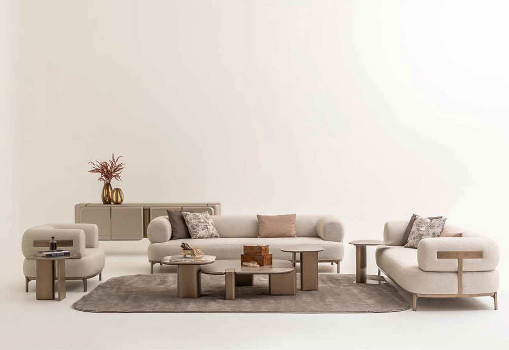 Neutral living room with cream sectional sofa, matching armchairs, round coffee tables, and a gray rug in a bright minimalist space.