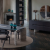 Modern dining room with a long black table black chair circular rug and turquoise glass vases overlooking a lake view through large windows