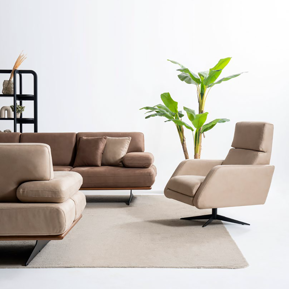 Modern beige sectional sofa set with matching armchair, a tall plant, and a black shelf against a white wall.