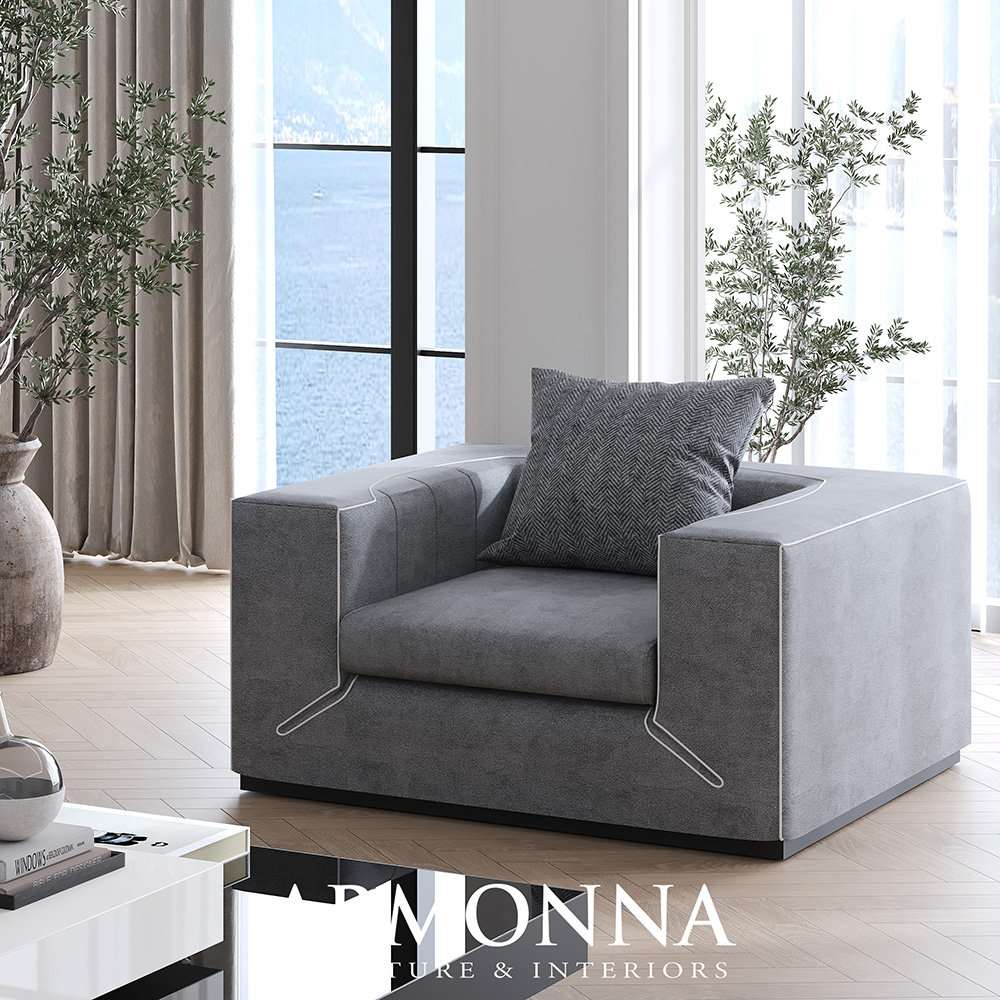 Modern gray armchair with a square design and a patterned throw pillow in a bright living room by large windows and greenery.