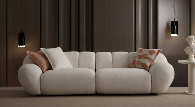 Cream modular sofa with rounded arms in a dark wood-paneled living room, flanked by pendant lights and pastel cushions.