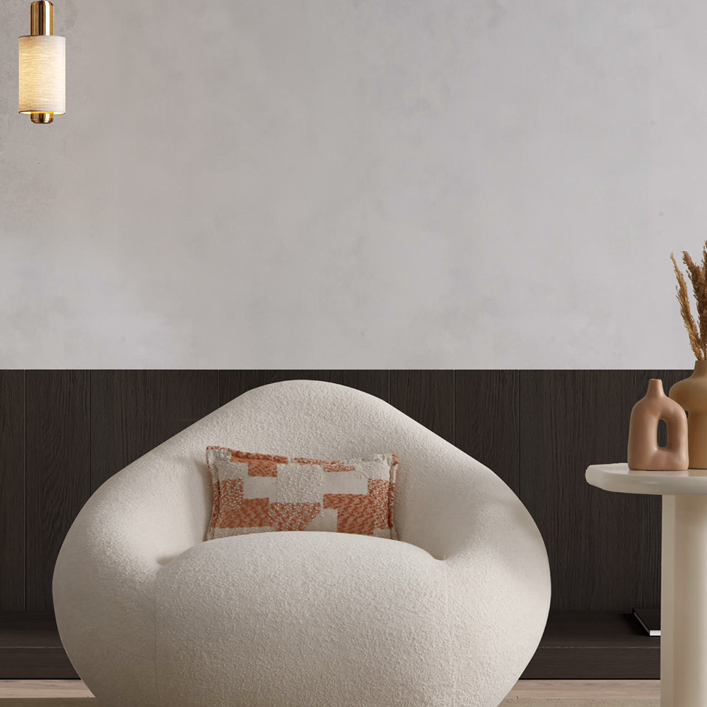 White rounded textured lounge chair with an orange geometric pillow in a modern living room setting.