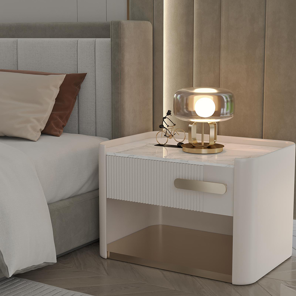 Monge Bedroom Custom Production 7 Armonna Modern bedroom nightstand with marble top white finish and gold accents lit by a rounded glass lamp a small bicycle figurine sits beside