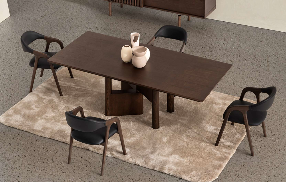 Dark wooden dining table with six black-and-wood chairs around it on a beige rug, topped with three ceramic vases as a centerpiece in a modern room.