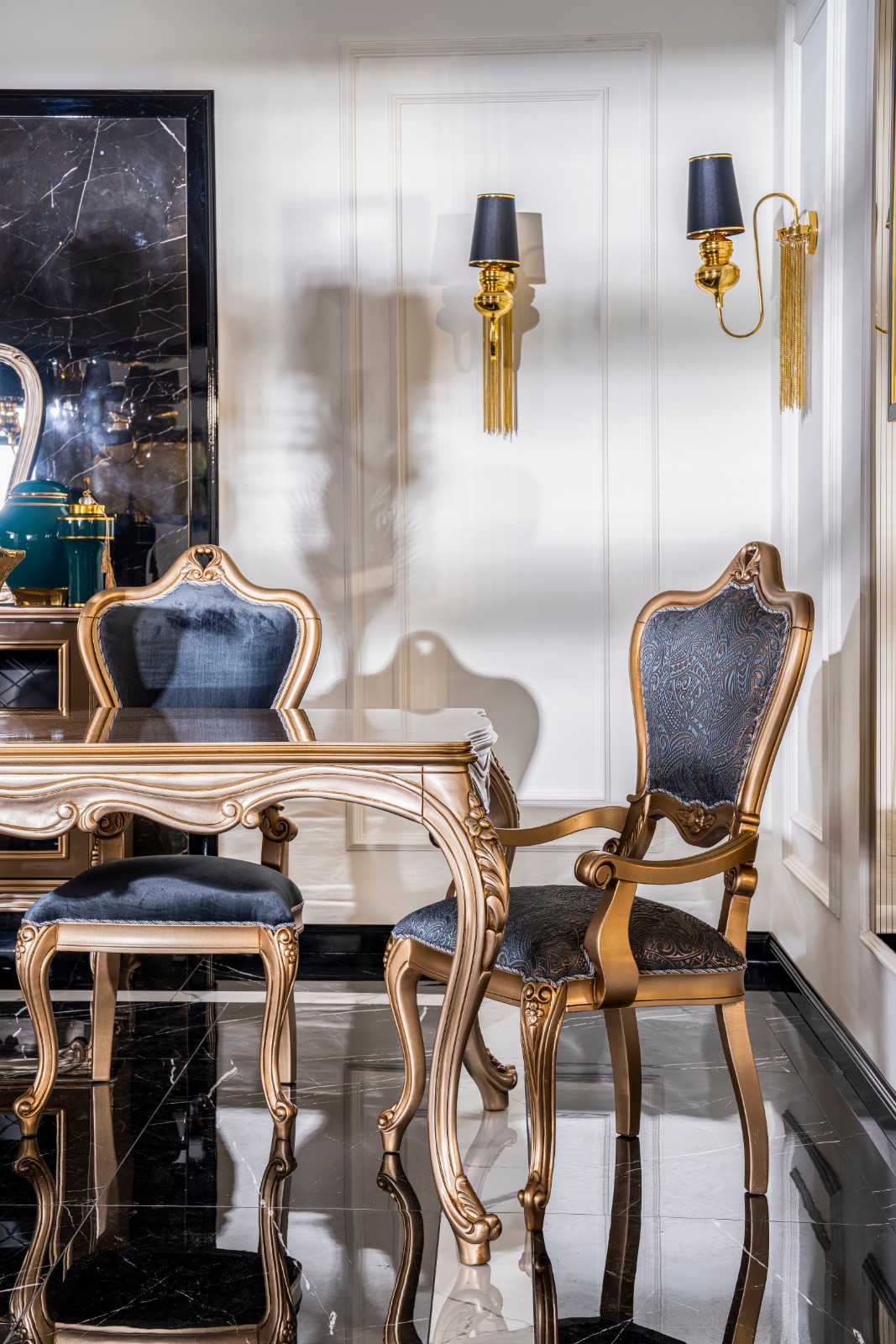 Napoli Classic Set 14 Armonna Luxurious dining room with a gold trimmed carved table and blue upholstered chairs black marble floor and gold wall sconces on cream walls