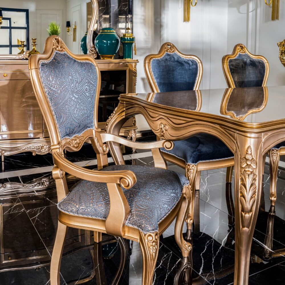 Luxurious dining room with gold-framed blue upholstered chairs around a glass-topped ornate table on a black marble floor.