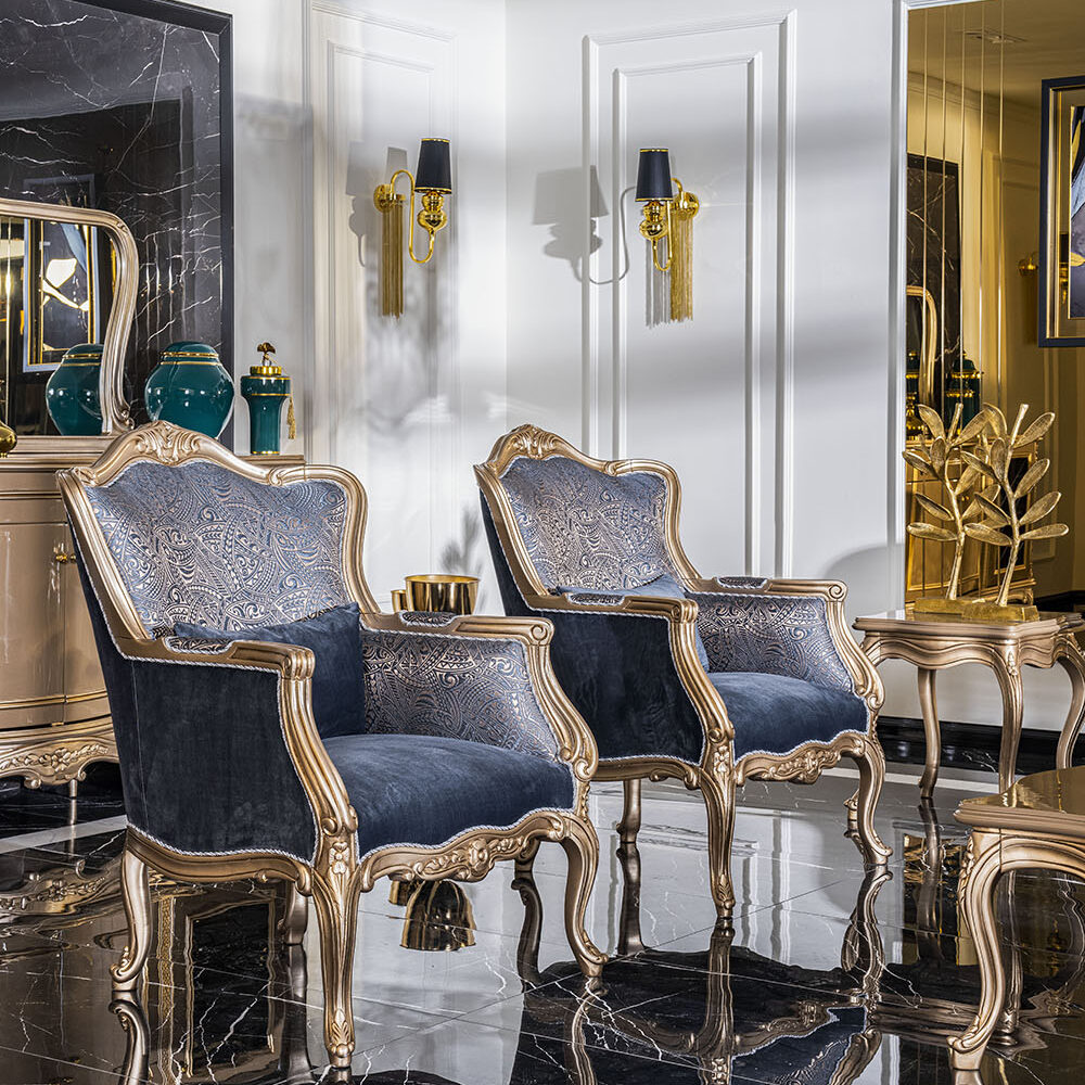 Luxurious seating area with gold-trimmed blue velvet chairs, marble floor, and gold accents.