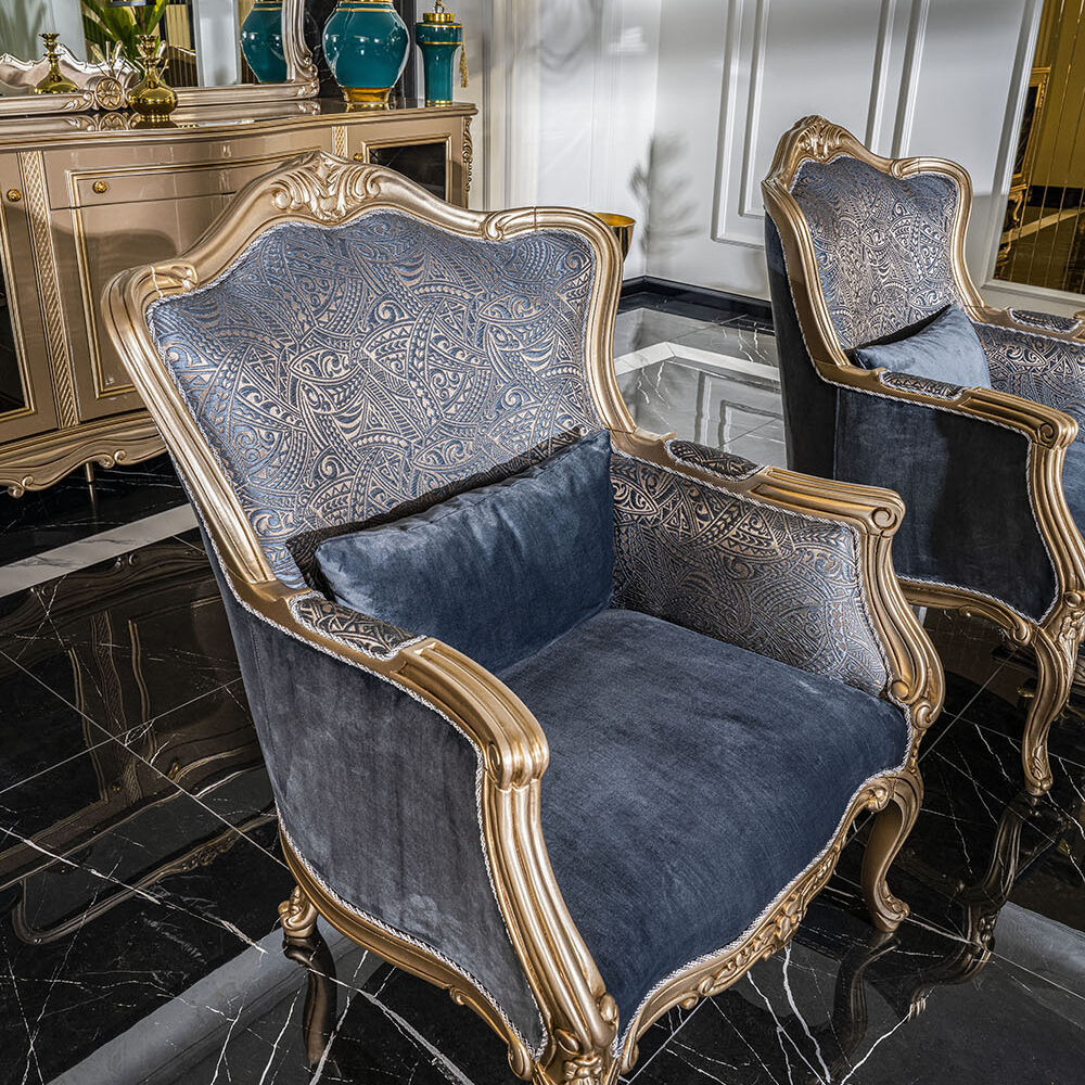 Luxurious living room with blue and gold upholstered armchairs, marble floor, and a mirrored sideboard.