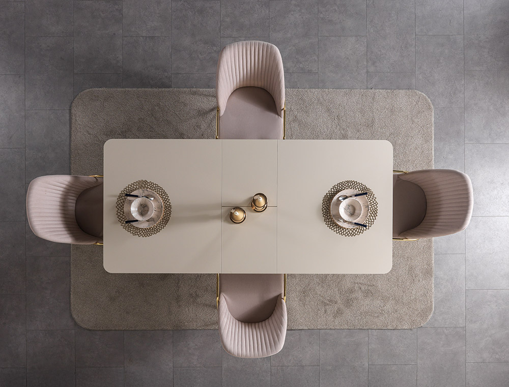 Nisan Dining Room and TV Unit 9 Armonna Top down view of a dining table set for four with blush pink upholstered chairs two place settings with glassware on decorative mats and gold saltpepper shakers on a beige table