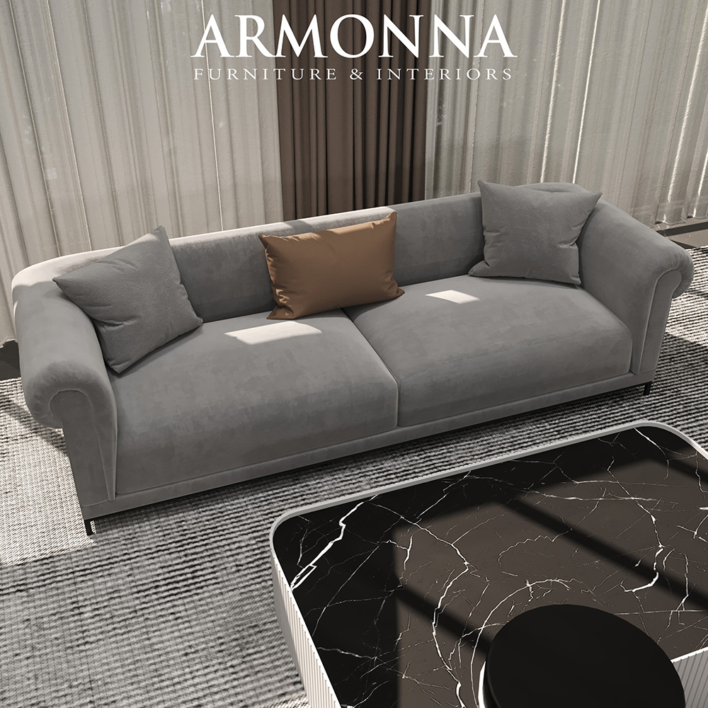 Gray fabric sofa with three cushions on a striped rug, showroom setting with Armonna Furniture & Interiors logo above.
