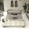 Modern white living room with a sectional sofa two armchairs a round coffee table rug TV stand and a tall plant